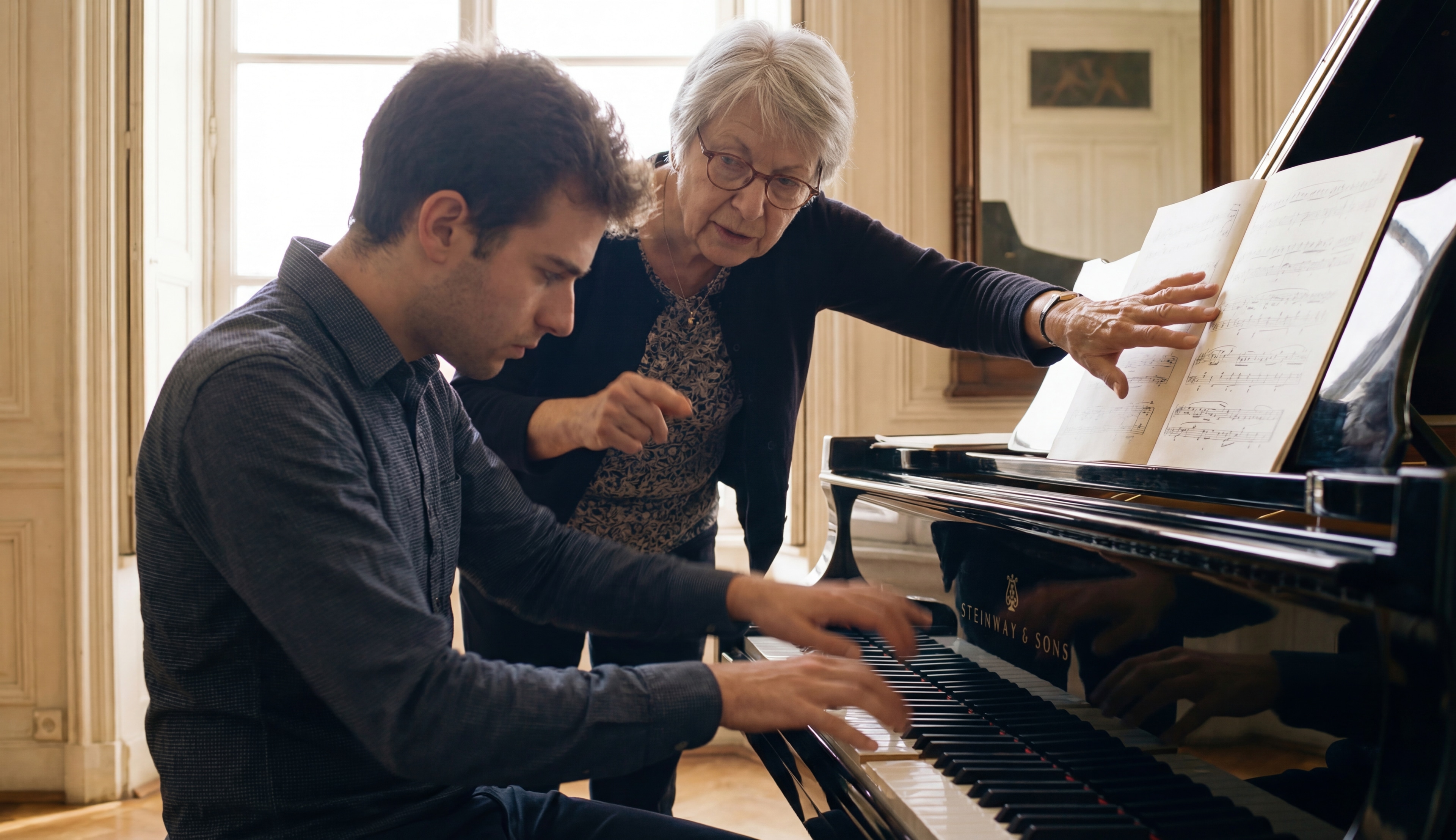 Piano teacher guiding a student's hands at a grand piano